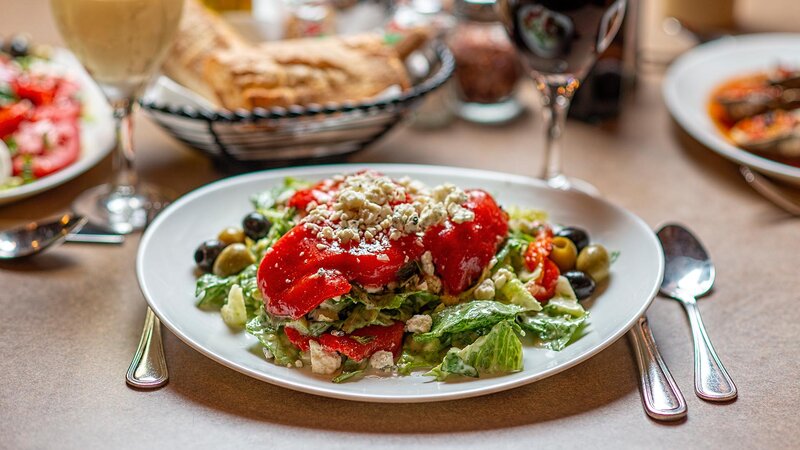 Salad topped with olives, red peppers and crumbled blue cheese