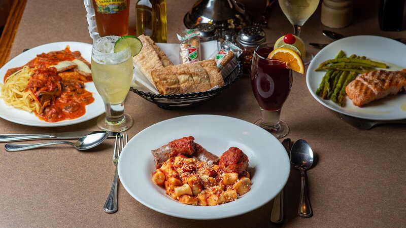 Several dinner entrees with focus on gnocchi pasta entree with a side of sausage