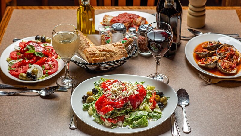 Several appetizers with focus on salad topped with olives, red peppers and crumbled cheese