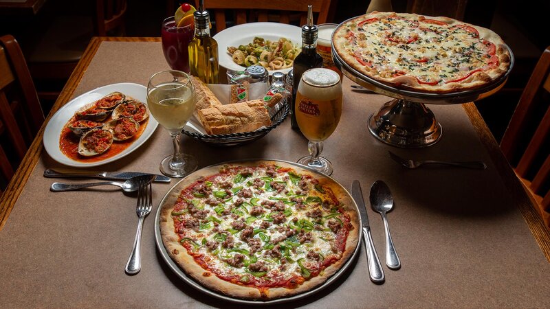 Multiple entrees with focus on pizza topped with green peppers and sausage